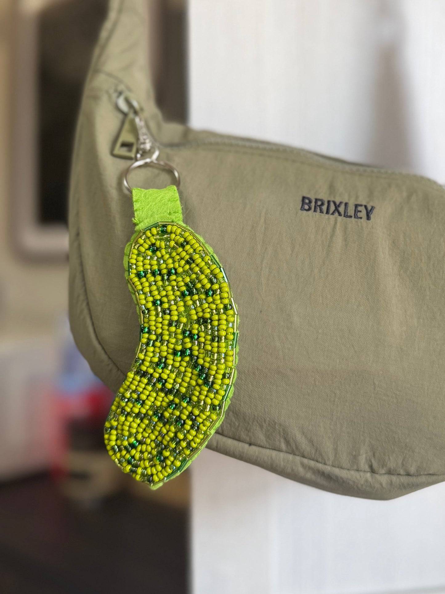 It features a bright lime green and yellow beaded keychain charm attached to a silver metal clasp.