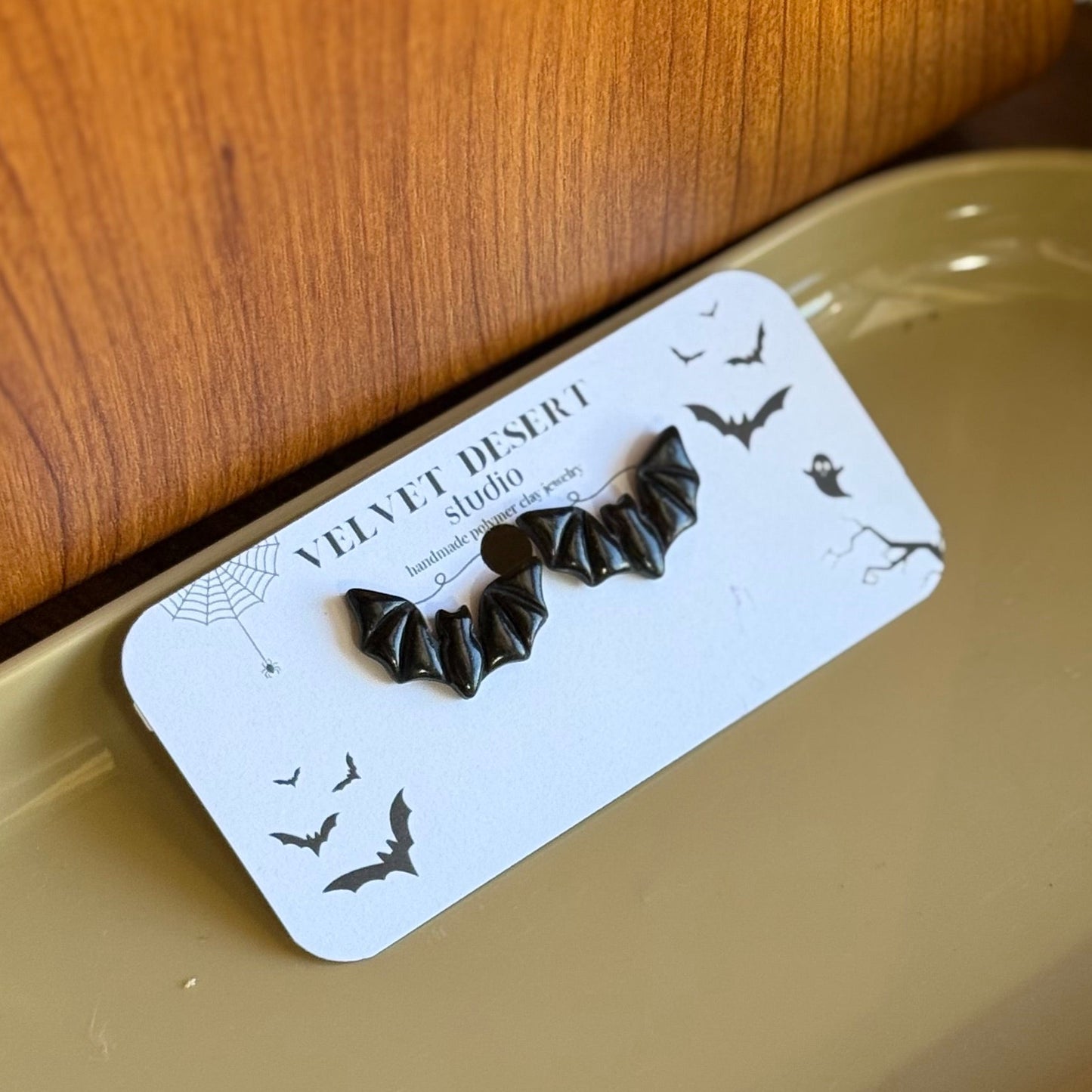 Pair of black earrings on a white card placed on a beige tray.