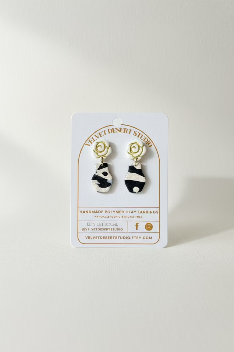 pair of vase earrings with rose shaped tops on a velvet desert studio product backing card on a white background.